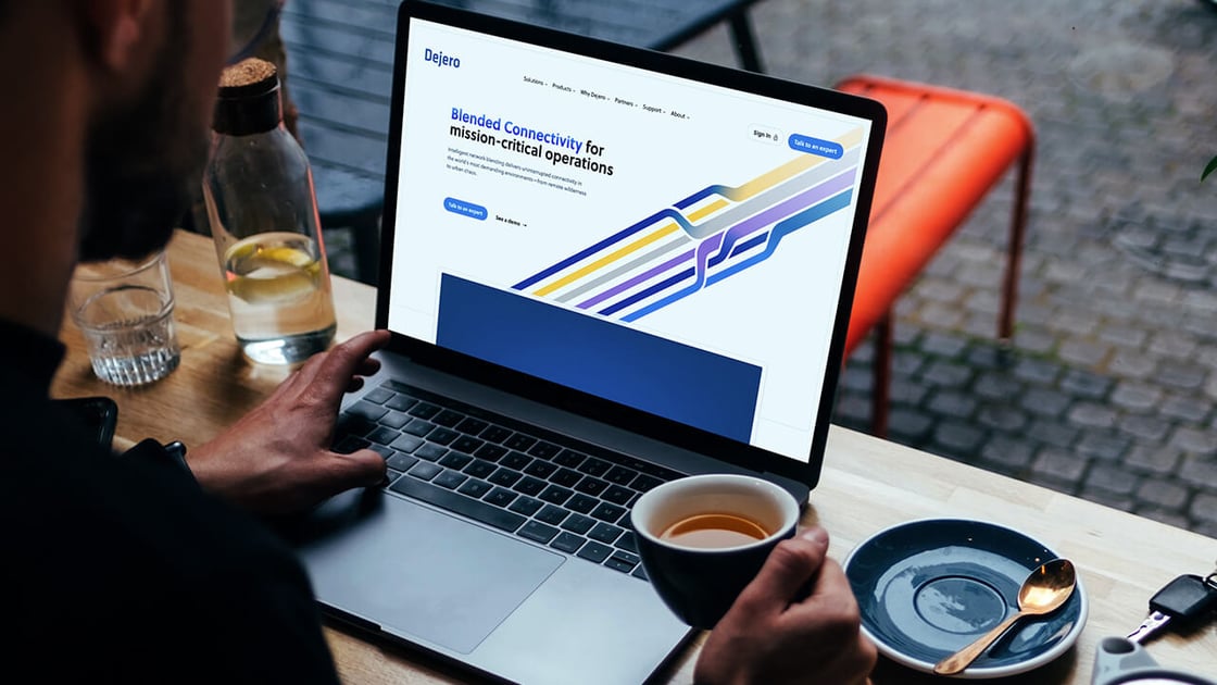 Person viewing the new Dejero website on a laptop while holding a coffee